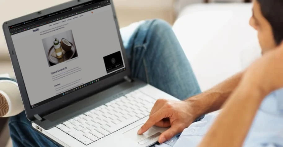 man on his laptop reading coconut oil as lube article